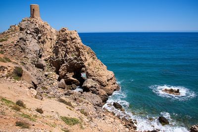 Rock formation on beach against clear blue sky