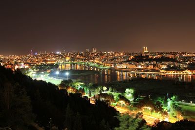 High angle view of illuminated buildings by river against sky