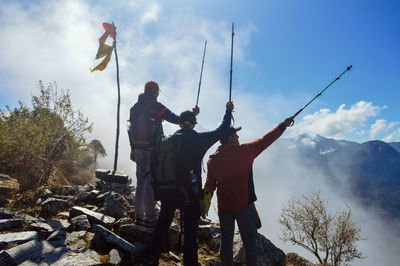 People standing by tree and mountain against sky