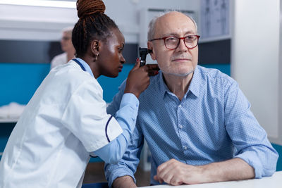 Female doctor examining ear of senior patient
