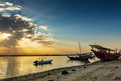 Boat moored on sea against sky during sunset