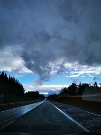 Road by trees against sky