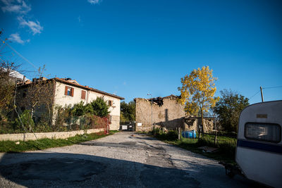 Road amidst trees and buildings against sky