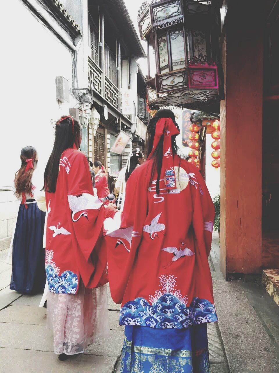 red, standing, building exterior, architecture, built structure, casual clothing, lifestyles, street, person, rear view, city, men, leisure activity, traditional clothing, text, three quarter length, day, outdoors