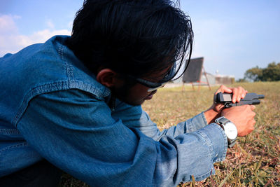 Side view of man holding camera on field