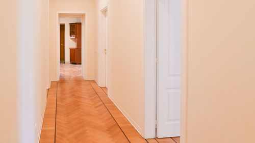 Corridor in a house with wooden floor white walls and doors to rooms.