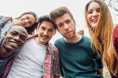 Low angle portrait of smiling friends standing outdoors