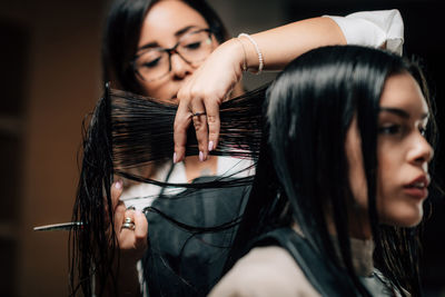 Close-up of hairdresser cutting woman hair in salon