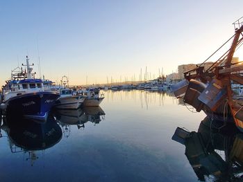 Boats moored in harbor at sunset