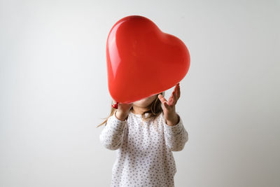 Portrait of woman holding heart shape against white background