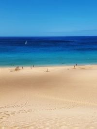 People at beach against clear sky