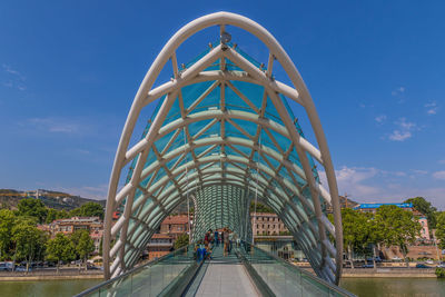 People walking in modern building against blue sky