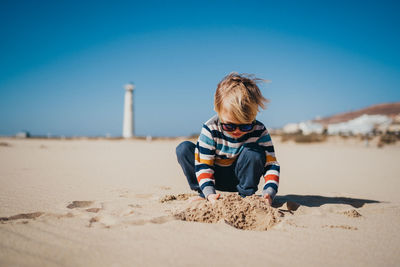 Boy child kid playing at the beach on a cold and windy day