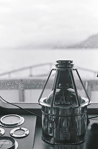 Close-up of wet glass window on table against sky