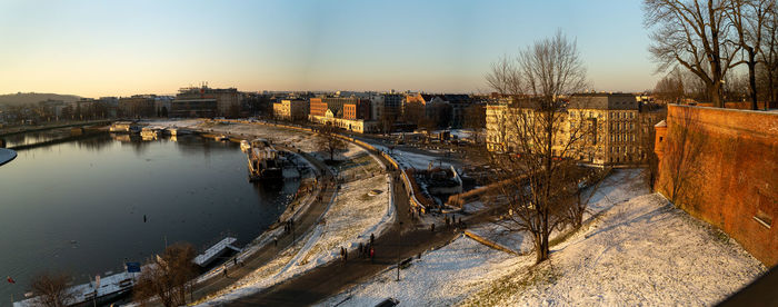 Bridge over river in city against clear sky during winter