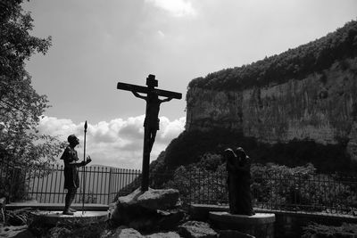 Low angle view of man standing on retaining wall against sky