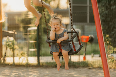 Full length of young woman swinging at playground