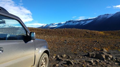 Car on snow covered landscape against sky