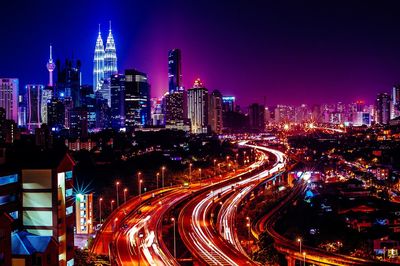 High angle view of light trails on road along illuminated city