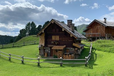 Built structure on field by houses against sky