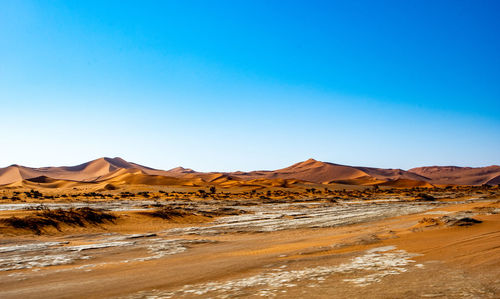 Scenic view of desert against clear blue sky