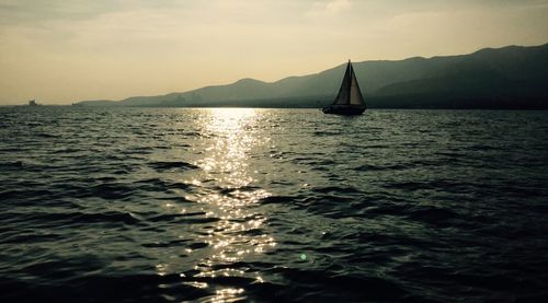 Sailboat sailing on sea against sky during sunset