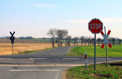 Road sign by street against sky