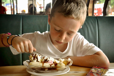 Boy eating banana with ice cream at restaurant