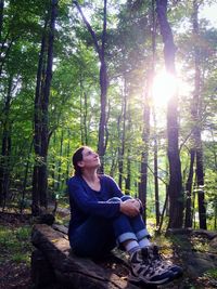 Young woman sitting on tree in forest
