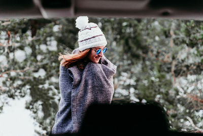 Woman wearing hat against trees during winter