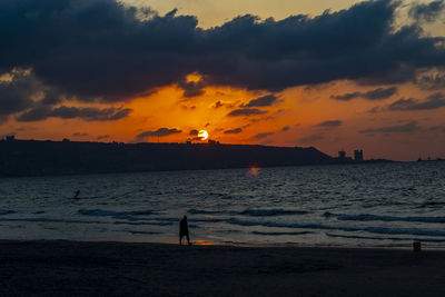 Silhouette person on beach against sky during sunset