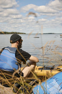 Man sitting and relaxing at lake near kayak