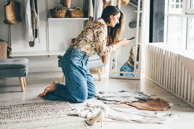 Full length of woman photographing clothes on ground