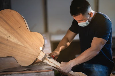 Craftperson making guitar at workshop