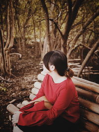 Woman sitting on bench at forest