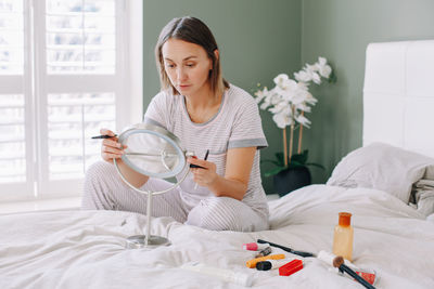 Young woman looking away while sitting on bed