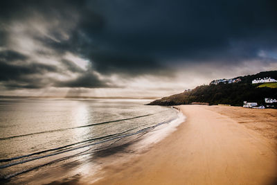 Scenic view of beach against cloudy sky