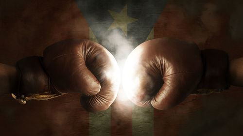 Cropped image of boxers fighting against illuminated puerto rican flag