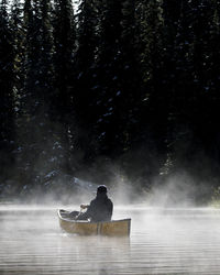 Rear view of man on boat at river