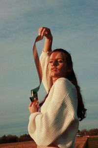 Side view of a young woman drinking against the sky