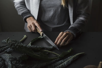 Midsection of woman cutting leaves 