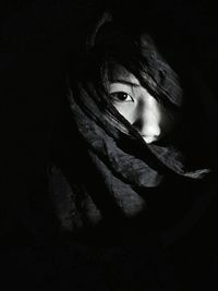 Portrait of serious young woman against black background