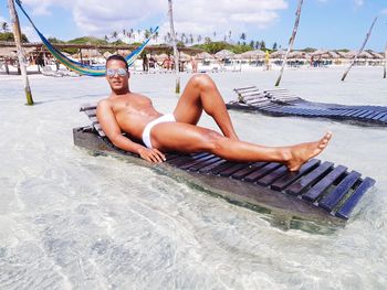 Young man lying on lounge chair at beach