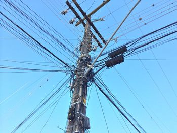 Low angle view of electricity pylon against clear blue sky