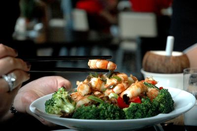 Close-up of hand holding food with chopsticks on table