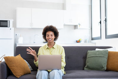 Young woman using laptop while sitting on sofa at home
