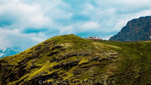 Scenic view of green mountains against cloudy sky