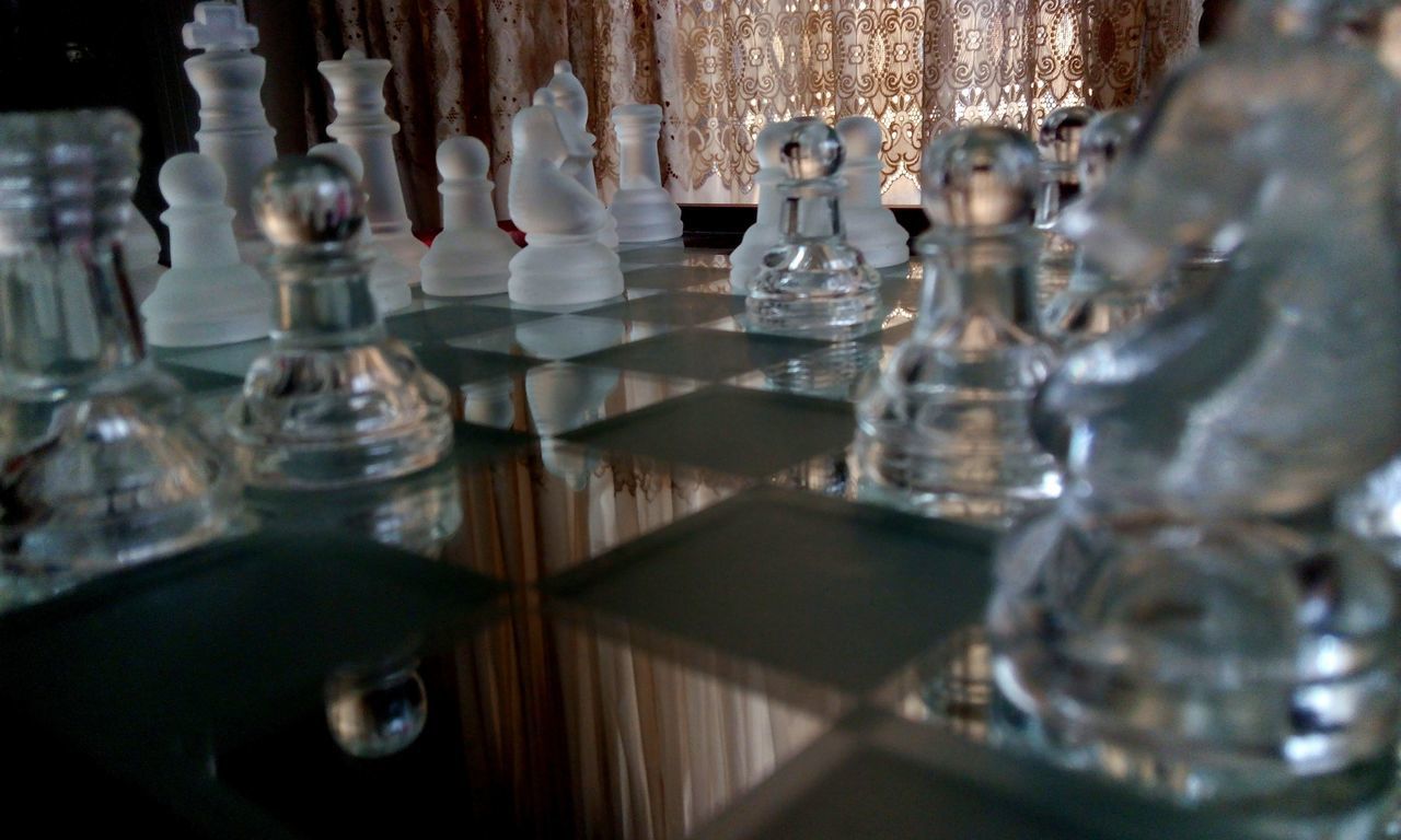 CLOSE-UP OF CHESS PIECES ON TABLE IN GLASS