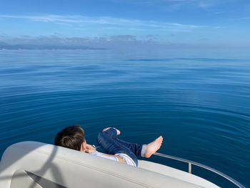 Rear view of woman looking at sea against blue sky