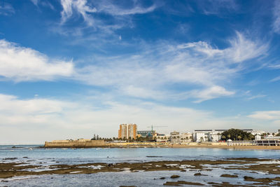 Sea by buildings against sky in city